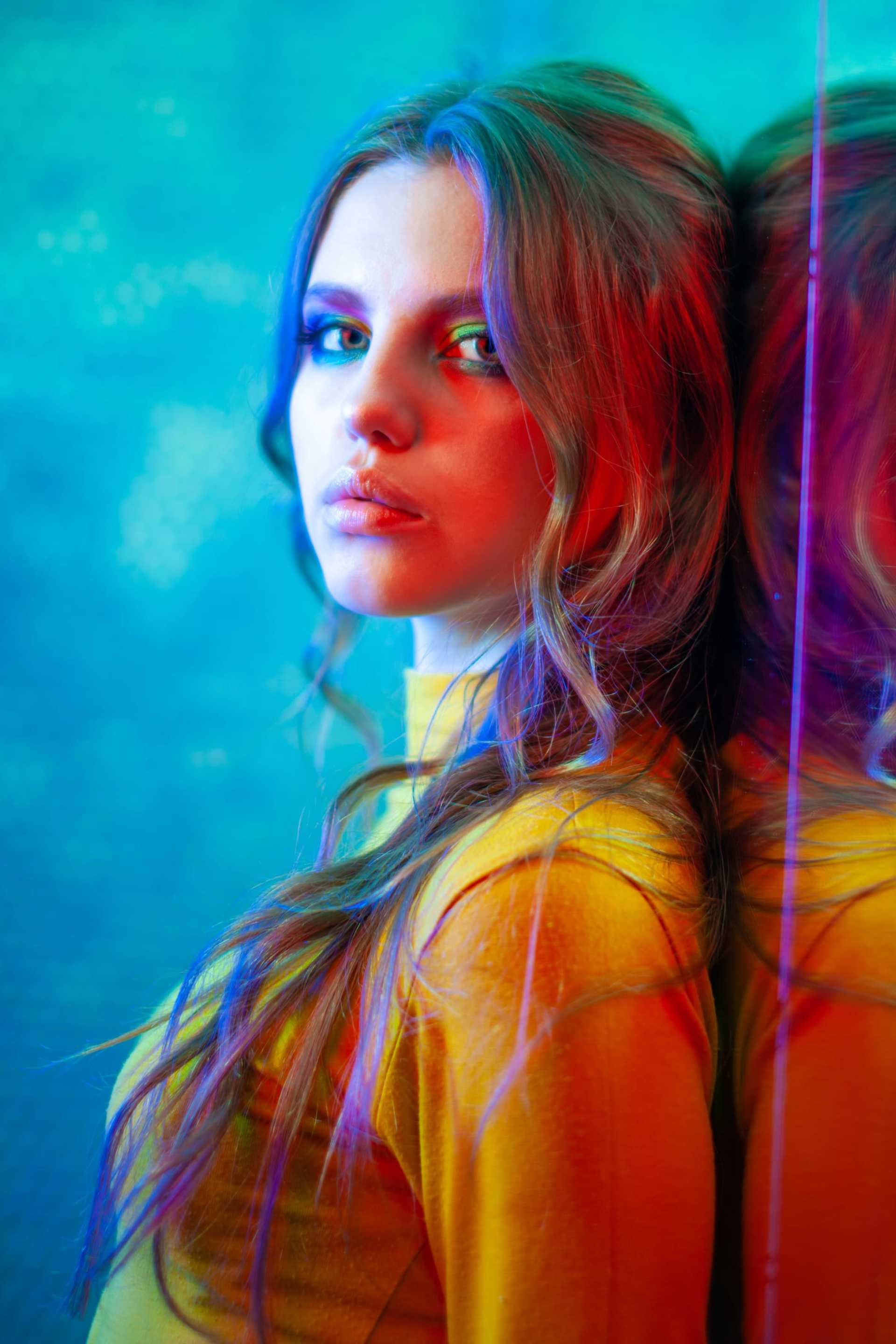 Young woman in vibrant lighting with colorful reflections.